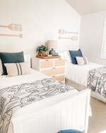 Two neatly made white bedroom beds with matching nightstand and decorative throw pillows.